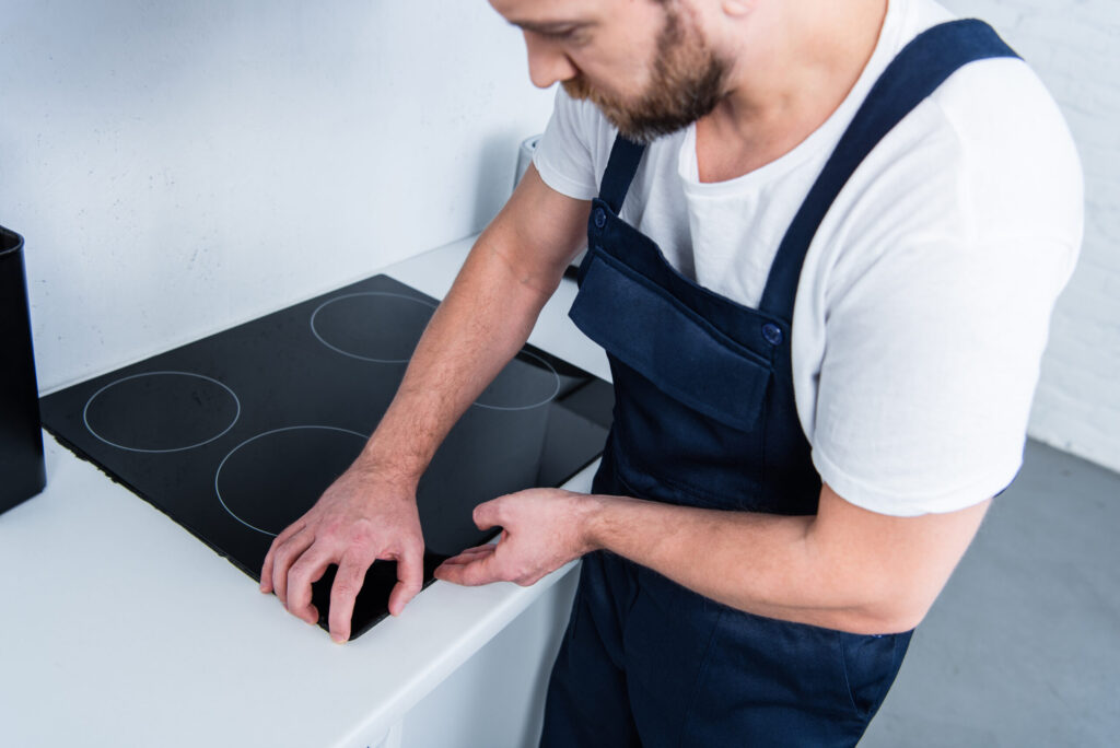 A repair man is fixing an electric stove top